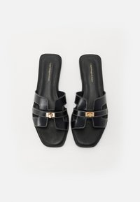 Sorte skinnsandaler med firkantet tå, flere stropper og en gullfarget spenne med hvite sømdetaljer.