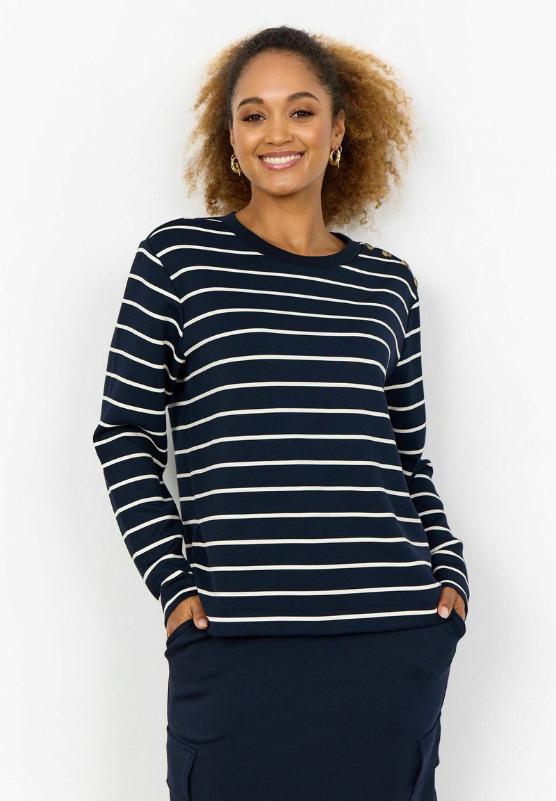 Navy and white striped long-sleeve top with round neckline, side pockets, and decorative buttons on one shoulder. Soft fabric, relaxed fit.