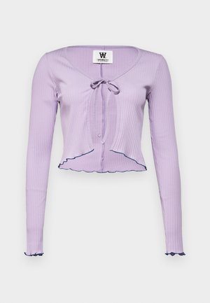 Top lilás de manga longa com textura canelada, decote em V, fecho frontal com laço, e bainha e punhos com babados acentuados com um acabamento azul escuro.