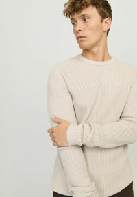 Jasno beżowy sweter z dzianiny o okrągłym dekolcie i ściągaczami, z teksturowanym wzorem i luźnym krojem.