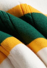 Tessuto morbido lavorato a maglia piegato, con strisce orizzontali nei colori bianco, giallo e verde scuro.