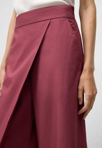 Bordeauxkleurige wijde broek met een gladde textuur, voorzien van voorplooien en een hoge taille. De stof lijkt lichtgewicht en duurzaam te zijn.
