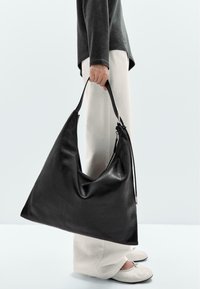 Schwarze Lederhandtasche mit dreieckiger Form und weicher, glatter Textur. Verfügt über einen einzelnen Tragegurt und einen silbernen Reißverschlussverschluss auf einer Seite.