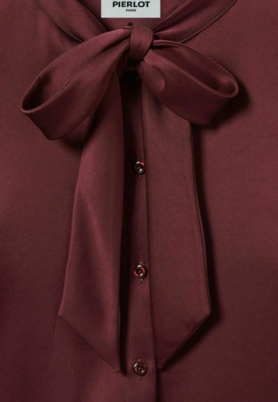 Blusa bordeaux in tessuto morbido con un fiocco al colletto e bottoni a contrasto. Etichetta con la scritta "PIERLOT PARIS."