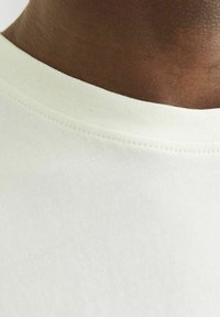 Lichtgekleurde T-shirt met een zachte, gladde structuur, een ronde hals en gelijkmatige stiksels langs de randen voor duurzaamheid.