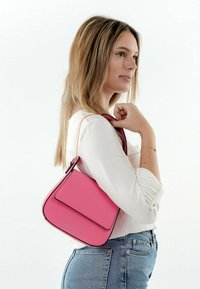 Bolso de mano de cuero rosa con una forma estructurada, que presenta un cierre de solapa, costuras en negro contrastantes y una correa corta para el hombro.