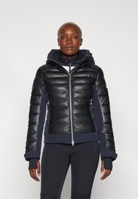 Giacca nera imbottita con cappuccio, dotata di sezioni trapuntate, polsini a coste e una zip argento. Realizzata con una combinazione di materiali.