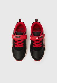 Chaussures de sport noires et rouges avec une surface lisse, fermeture lacets et scratch, col rembourré et détail graphique "Lightning McQueen".