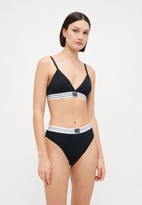 Black lingerie set featuring a triangular bralette with adjustable straps and matching high-waisted briefs, both with white striped elastic bands.