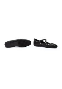 Zapatos planos negros de cuero con un diseño perforado, con tachuelas decorativas plateadas y una suela de goma texturizada.