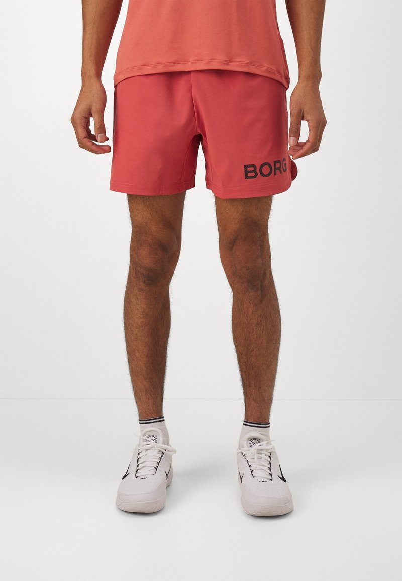 Rosa badshorts med svart "BORG"-text, tillverkade av lätt material med en enkel design. Matchas med vita sportskor.