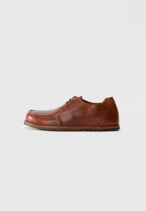 Chaussure marron en cuir à lacets pour homme avec une surface texturée et une semelle en caoutchouc, présentée de profil sur un fond blanc uni.