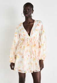 Vestido transparente con estampado floral en suaves colores pastel, con largas mangas abullonadas, escote en V profundo y detalle de dobladillo en capas y volantes.