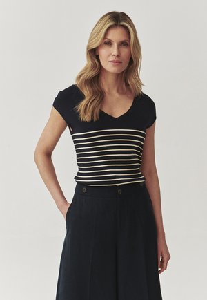 Navy-blaues V-Ausschnitt-Oberteil mit weißen horizontalen Streifen, kurzen Ärmeln und figurnaher Taille, kombiniert mit hoch taillierten dunklen Hosen.