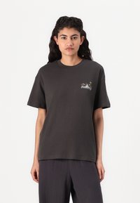 T-shirt in cotone grigio scuro con maniche corte, scollatura rotonda e piccola stampa grafica colorata nella zona sinistra del petto.