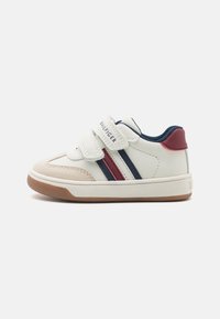White sneaker with velcro straps, featuring red and navy stripes. Soft suede toe cap, rubber sole, and a textured heel accent in maroon.