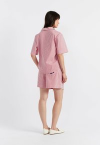 Robe à manches courtes et col, avec des rayures verticales rouges et blanches. Présente un ourlet de couleur unie et une poche arrière avec un détail de logo.