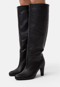 Stivali neri alti fino al ginocchio realizzati in materiale strutturato con un motivo intrecciato, dotati di punta affusolata e tacco alto affusolato.