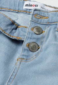 Pantalones cortos de mezclilla azul claro con costuras naranjas en contraste, que cuentan con dos botones de metal y una etiqueta que dice "minoti" cerca de la cintura.