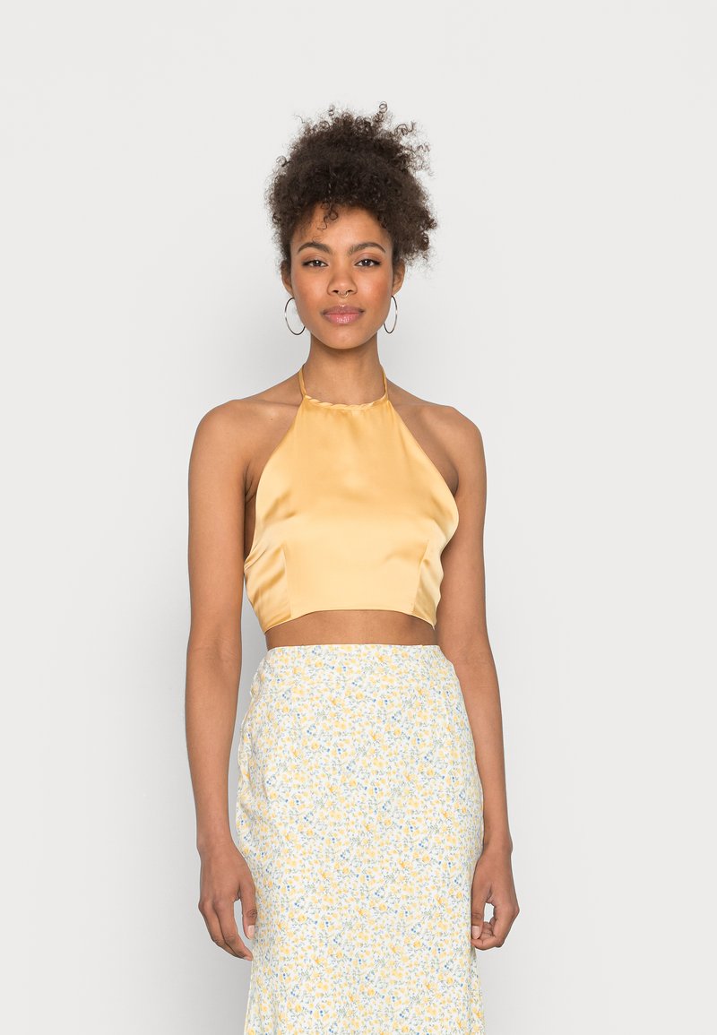 Top cropped em cetim amarelo com uma textura suave, combinado com uma saia de padrão floral em tons de amarelo e azul, apresentando um corte reto.