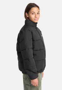 Giubbotto imbottito nero con colletto alto, design trapuntato e polsini elasticizzati, dotato di zip frontale e di un piccolo logo sul petto.