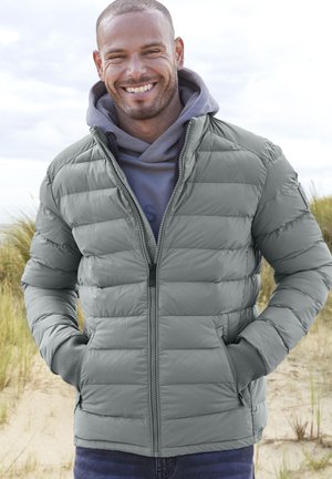 Küljeltalitatud hall jope, millel on lukuga sulgemine, soonikkoes varrukad ja küljetaskud, halli huudi peal. Esitatud liivase taustaga.