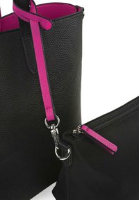 Bolso tote negro texturizado con una correa rosa, que presenta herrajes plateados. Un pequeño estuche negro con cremallera y un detalle de cremallera rosa está cerca.