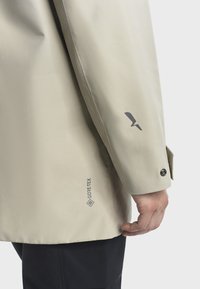 Bežna GORE-TEX jakna glatke teksture, sa logotipom na rukavu i dugmadi na manžetama. Jednostavan, funkcionalan dizajn.