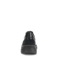 Baskets noires présentant un mélange de textures en vernis et en daim, de forme arrondie, avec une semelle épaisse et un design minimaliste sans marquage visible.