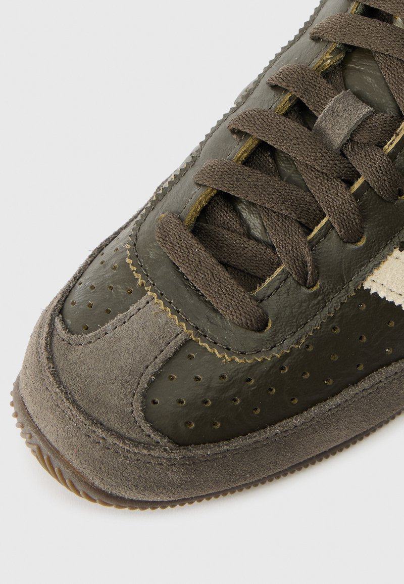 Donkergroene leren en suède sneakers met perforaties, bruine veters en een getextureerde zool. Heeft een gebogen neus en contrasterende stiksels.
