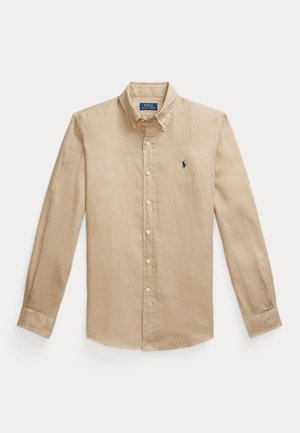 Cămașă bej cu mânecă lungă și nasturi, fabricată din in, având un guler clasic și un mic logo bleumarin pe partea stângă a pieptului.