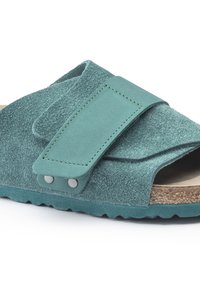Teal ruskindsandal med en bred justerbar rem, metal accenter og struktureret fodseng på en kontureret korksål.