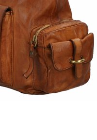 Borsa in pelle marrone con chiusura a zip, tasca frontale con pattina e un accento decorativo in anello color oro. Finitura morbida e testurizzata.