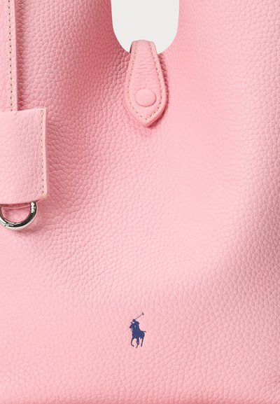 Ροζ δερμάτινη τσάντα tote με υφή, διαθέτει κλείσιμο με κουμπί, μεταλλική λεπτομέρεια σε σχήμα δακτυλίου και μικρό μπλε λογότυπο με ένα καβαλάρη.