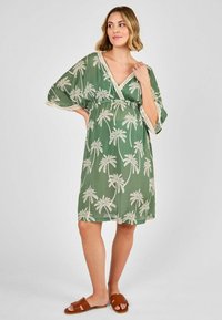 Grünes Kleid mit tropischem Druck und Palmenmotiv, weiten Ärmeln, V-Ausschnitt, tailliertem Bund und beigen Spitzenakzenten an den Ärmeln.