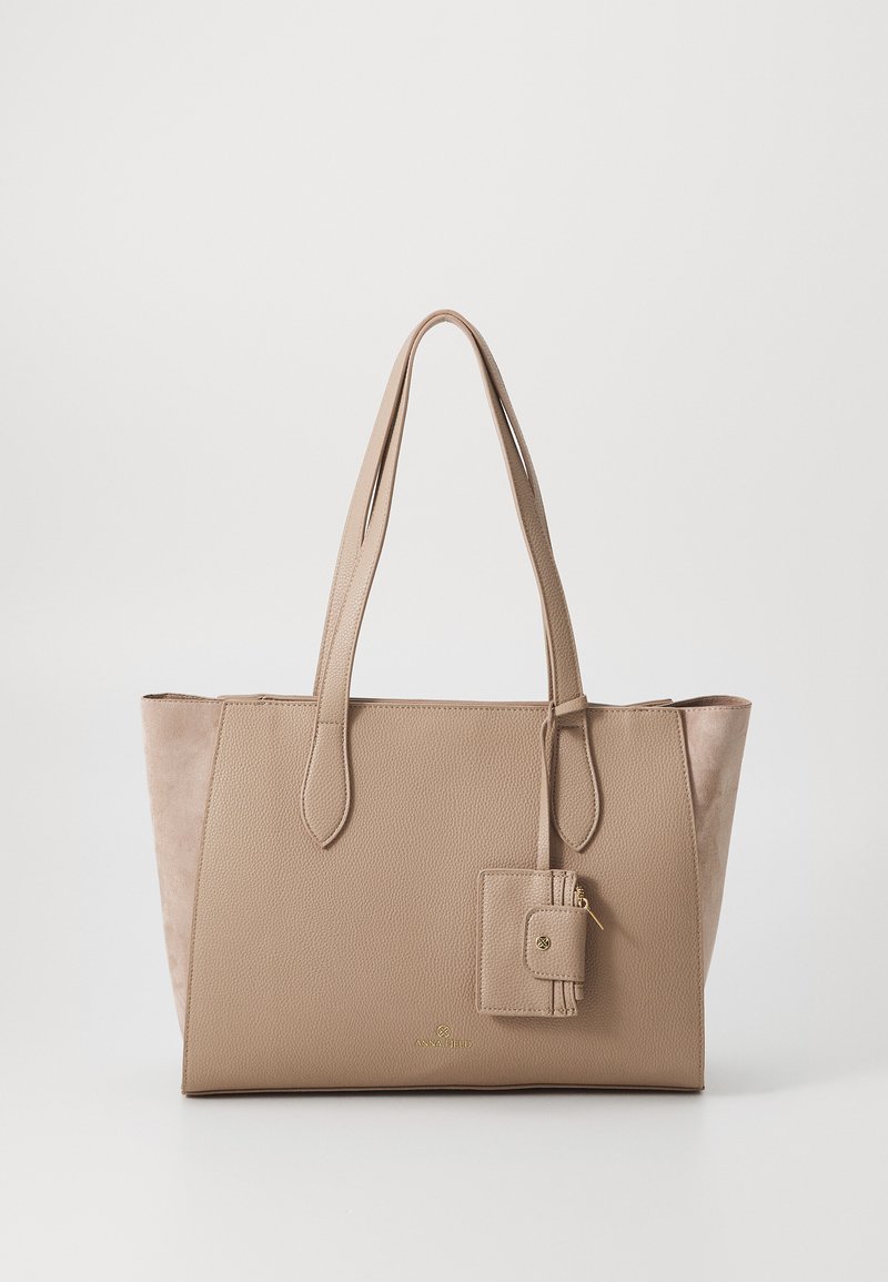 Beige schoudertas van textuur faux leer, met twee lange straps en een kleine ritszak eraan bevestigd. Heeft een zijdezachte nubuckachtige kant.
