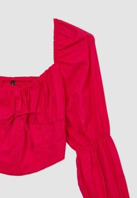 Blusa rossa, corta, con scollatura quadrata, maniche lunghe a sbuffo, texture arricciata e dettaglio con coulisse in vita. Tessuto morbido.