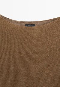 Maglione marrone lavorato a maglia con scollo rotondo e una etichetta nera all'interno del colletto con la scritta "Massimo Dutti Made in China".