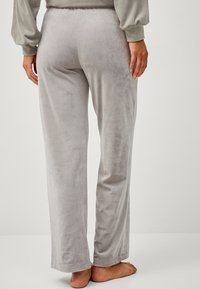Pantalons de lounge gris, extensibles, avec une texture douce et veloutée, design à jambes droites et taille élastique. Pas de motifs ni de pièces métalliques visibles.