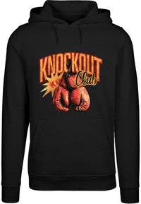 Felpa nera con cappuccio caratterizzata da una stampa grafica di guantoni da boxe rossi, il testo "KNOCKOUT" in grassetto e accenti in stile fumetto esplosivi gialli e arancioni.