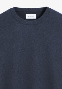 Marinblått stickat tröja med rund halsringning, ribbade mudd och nederkant. Har en liten, subtil logotyp framtill nära nederkanten.