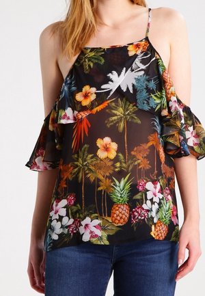 Czarna bluzka z odkrytymi ramionami z kolorowym tropikalnym wzorem palm, kwiatów hibiskusa i ananasów, noszona z niebieskimi dżinsami.