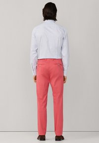 Lichtblauw-wit gestreept overhemd met lange mouwen, gecombineerd met roze chino's. De chino's hebben twee achterzakken en een slanke pasvorm.