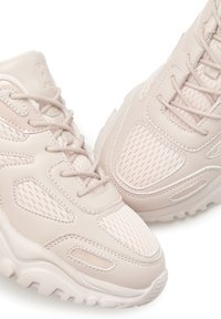 Chaussures de sport rose clair en mesh et matériau synthétique, avec un design texturé, un col rembourré et une semelle en caoutchouc épaisse.