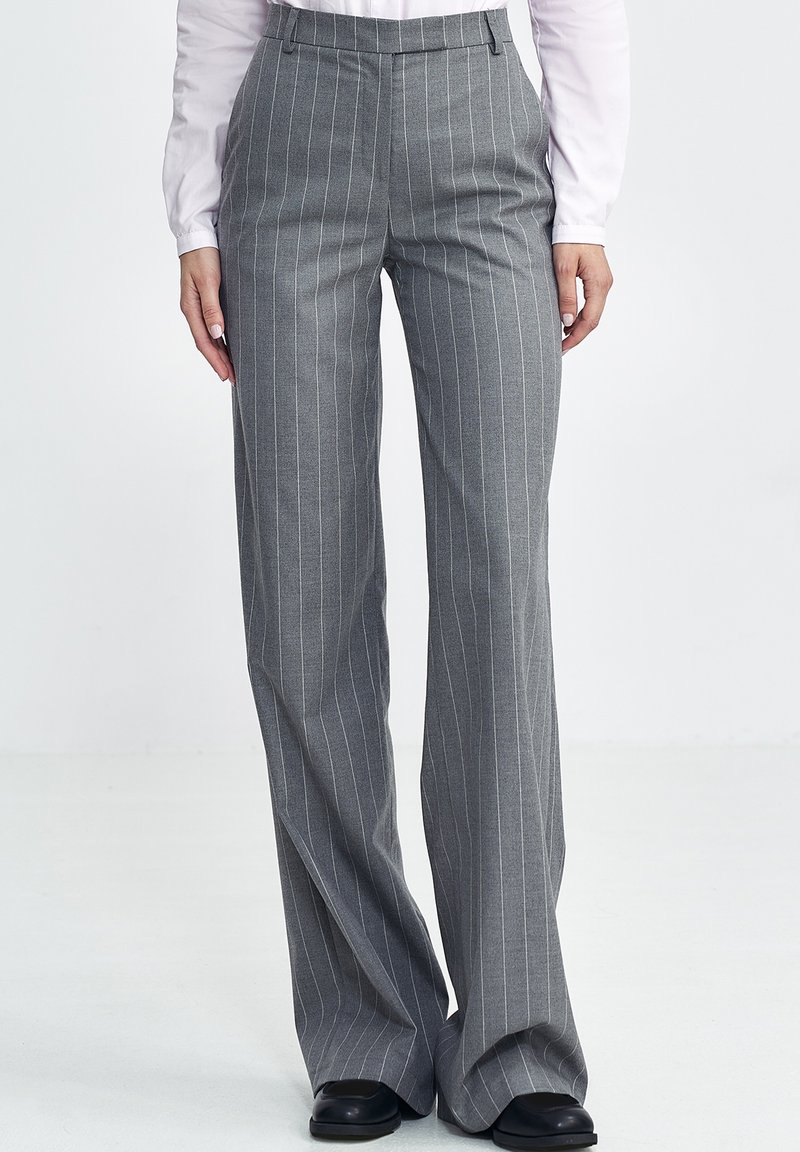 Szare, w pasiaki spodnie o rozszerzanym kształcie, z gładką teksturą i dopasowanym fasonem. Zawierają szlufki na pasek oraz kieszenie boczne.