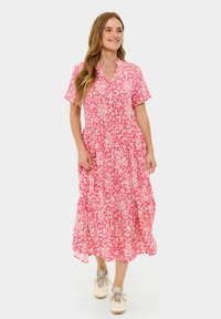 Roze bloemen midi-jurk met korte mouwen, v-hals, uitlopende rok en lichte stof, gestyled met beige sneakers.