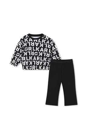Zwart-wit longsleeve top met gedurfde KARL-tekst en grafische gezichten, gecombineerd met effen zwarte broek met KARL LAGERFELD tailleband.
