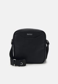 Borsa a tracolla in materiale sintetico nero con superficie texturizzata, dettaglio di cuciture diagonali e tracolla regolabile; presenta una placca con il logo frontale per l'identificazione del marchio.