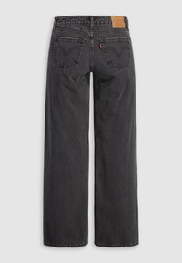 Jean en denim noir à jambes larges, vu de dos avec deux poches et un patch de marque en cuir marron sur la ceinture.