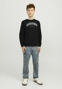 Čierne tričko s dlhými rukávmi a bielym grafickým nápisom "JACK&JONES", spárované so svetlomodrými cargo džínsami, ktoré majú niekoľko vreciek a voľný strih.